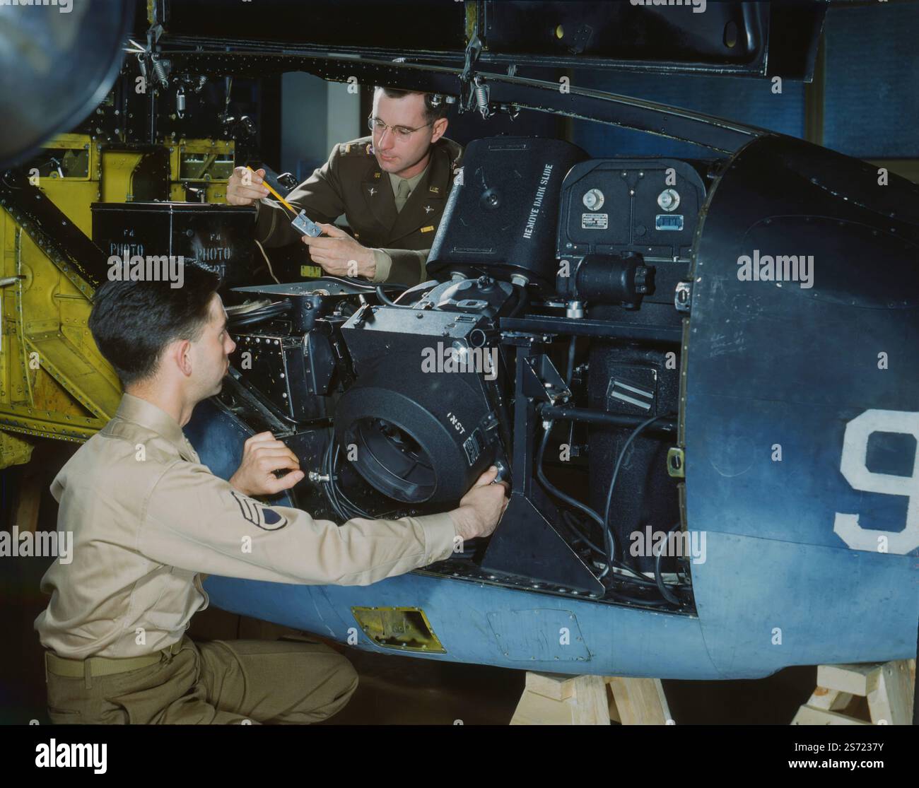 Flugzeugbauer, die am Trimetrogon Kamerasystem arbeiten. Die Lockheed P-38M Lightning war ein US-amerikanisches Kampfflugzeug mit Doppelkolbenmotor, das als einsitziges Flugzeug entwickelt wurde. Es wurde für das United States Army Air Corps (USAAC) im Zweiten Weltkrieg entwickelt und enthielt ein markantes Doppelbogendesign mit einem zentralen Maschinenhaus, das das Cockpit und die Bewaffnung enthielt. Neben seiner Rolle als allgemeiner Jagdflugzeug war die P-38 ein hochwirksamer Jagdbomber, ein Nachtjäger und ein Langstreckeneskortjäger, wenn sie mit Sprungpanzern ausgestattet war. Der P-38 wurde auch als Bomber-pathfinder und als Luftaufnahmegerät verwendet Stockfoto