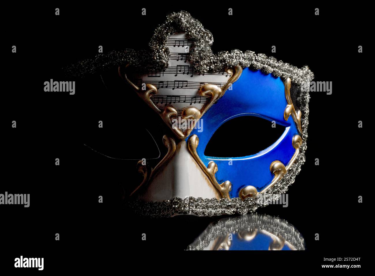 Kleine venezianische Karnevalsmaske, die im Dunkeln auftaucht, kostbare Details beleuchtet, schwarzer Hintergrund, farbige Reflexionen und Kopierraum für Design. Stockfoto