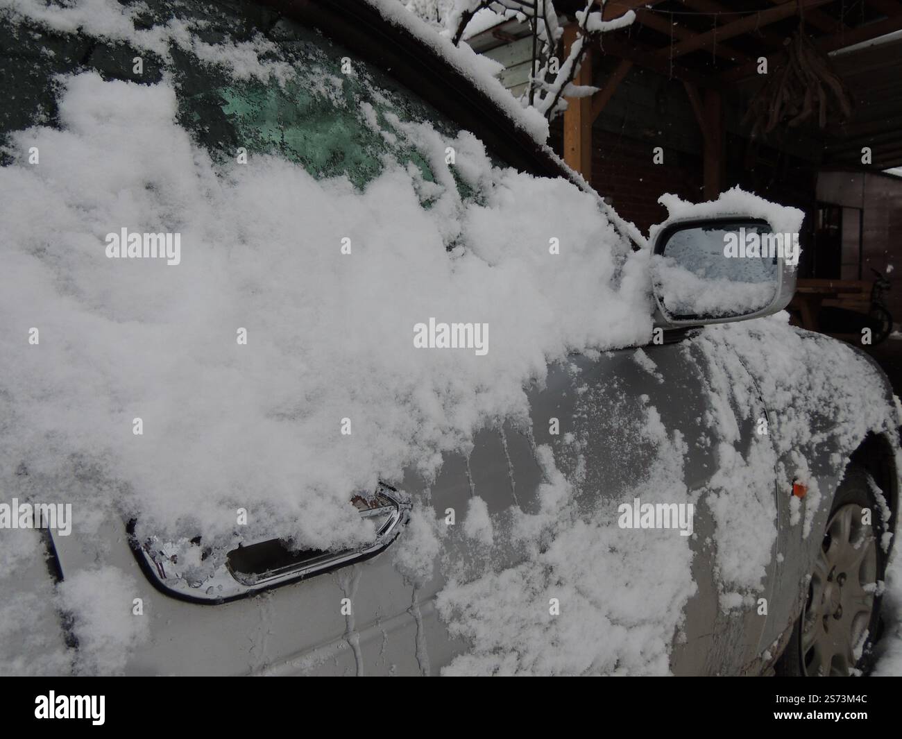 Seite des eisgrauen Autos mit Schnee bedeckt, Problem beim Öffnen der Fahrzeugtür nach Schneesturm, eiskalter Regen und extremer Temperaturabfall Stockfoto
