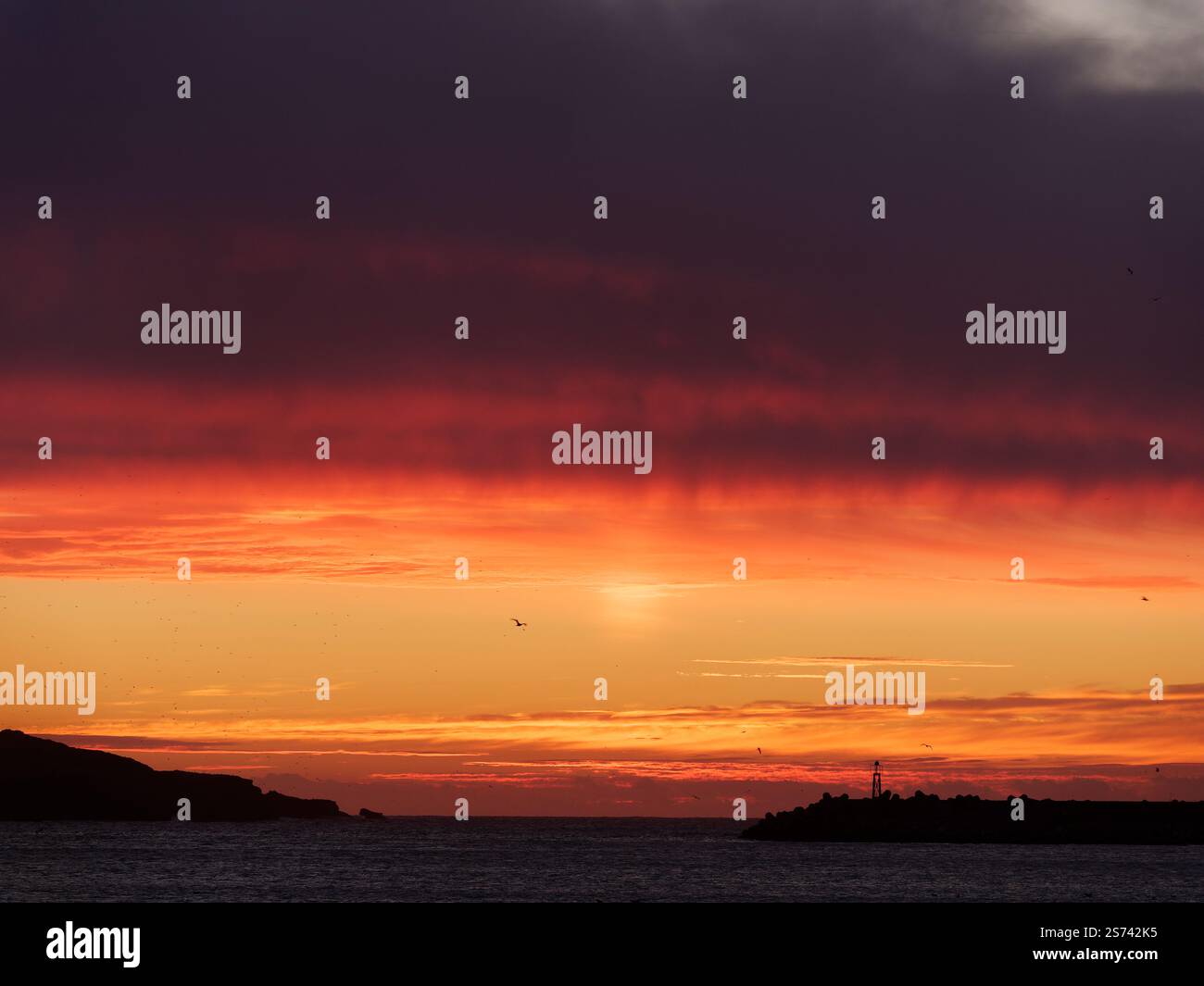 Dramatische dunkle Wolken bei Sonnenuntergang über einer Insel vor der Küste von Essaouira, Marokko. Januar 2025 Stockfoto