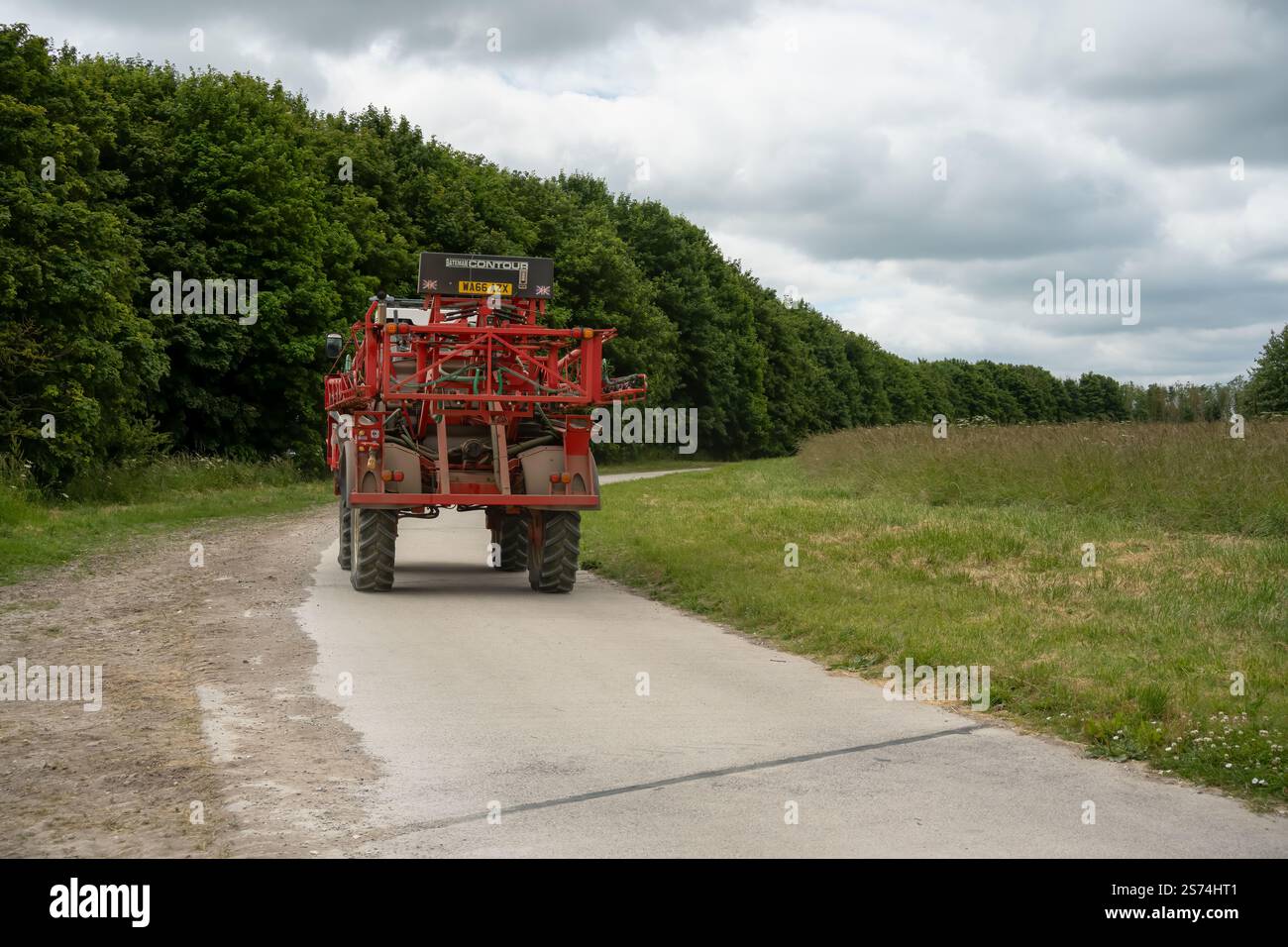 Eine große Feldspritze für Rotwein in Aktion auf einem Feld mit Jungweizen Stockfoto