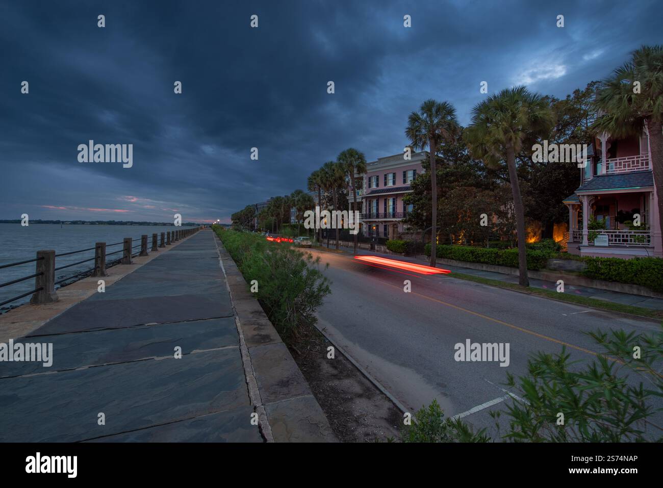 Charleston SC – 20. September 2023; historische architektonische Häuser säumen die Battery Street entlang der Bucht bei Nacht mit Lichtspuren von vorbeifahrenden Autos. Stockfoto