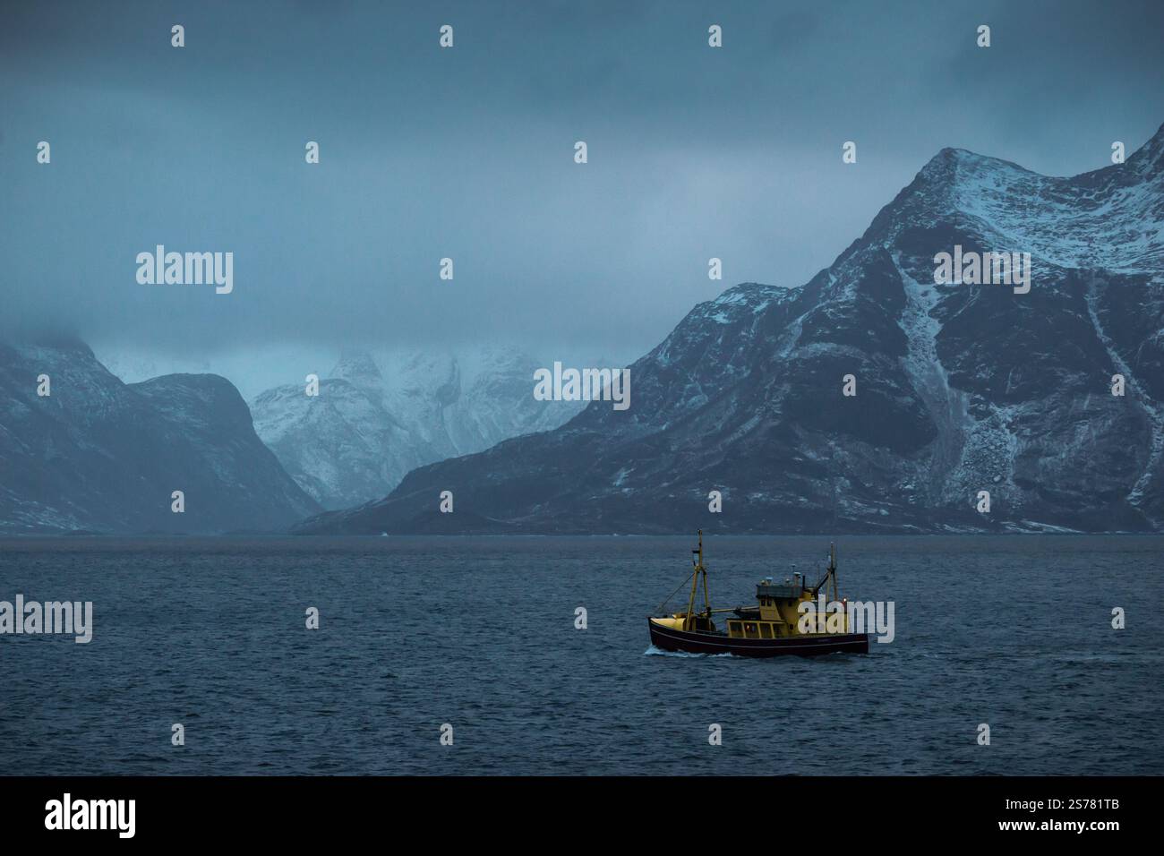 Eine atemberaubende norwegische Landschaft mit schneebedeckten Bergen, einem ruhigen Fjord und einem Boot auf dem Wasser. Eine ruhige und kalte Szene, ideal für Landschaftsfotografie. Stockfoto