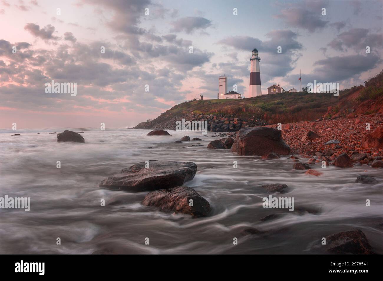 Ein Langzeitfoto des Montauk Lighthouse in New York, bei dem Meereswellen gegen die Küste krachen. Eine ruhige und ikonische Küstenszene. Stockfoto