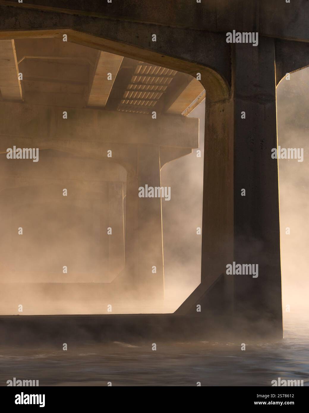 Eine kleine Brücke, die von unten gefangen wurde, in Nebel gehüllt und in warmes Morgenlicht getaucht ist. Eine ruhige und stimmungsvolle Architekturszene. Stockfoto