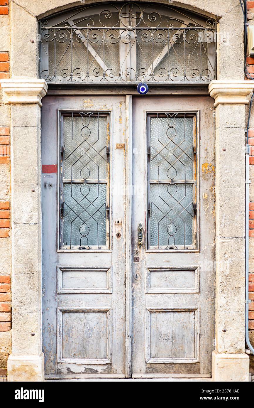Rustikale Holztür mit Metallgitter und roter Ziegelwand. Stockfoto