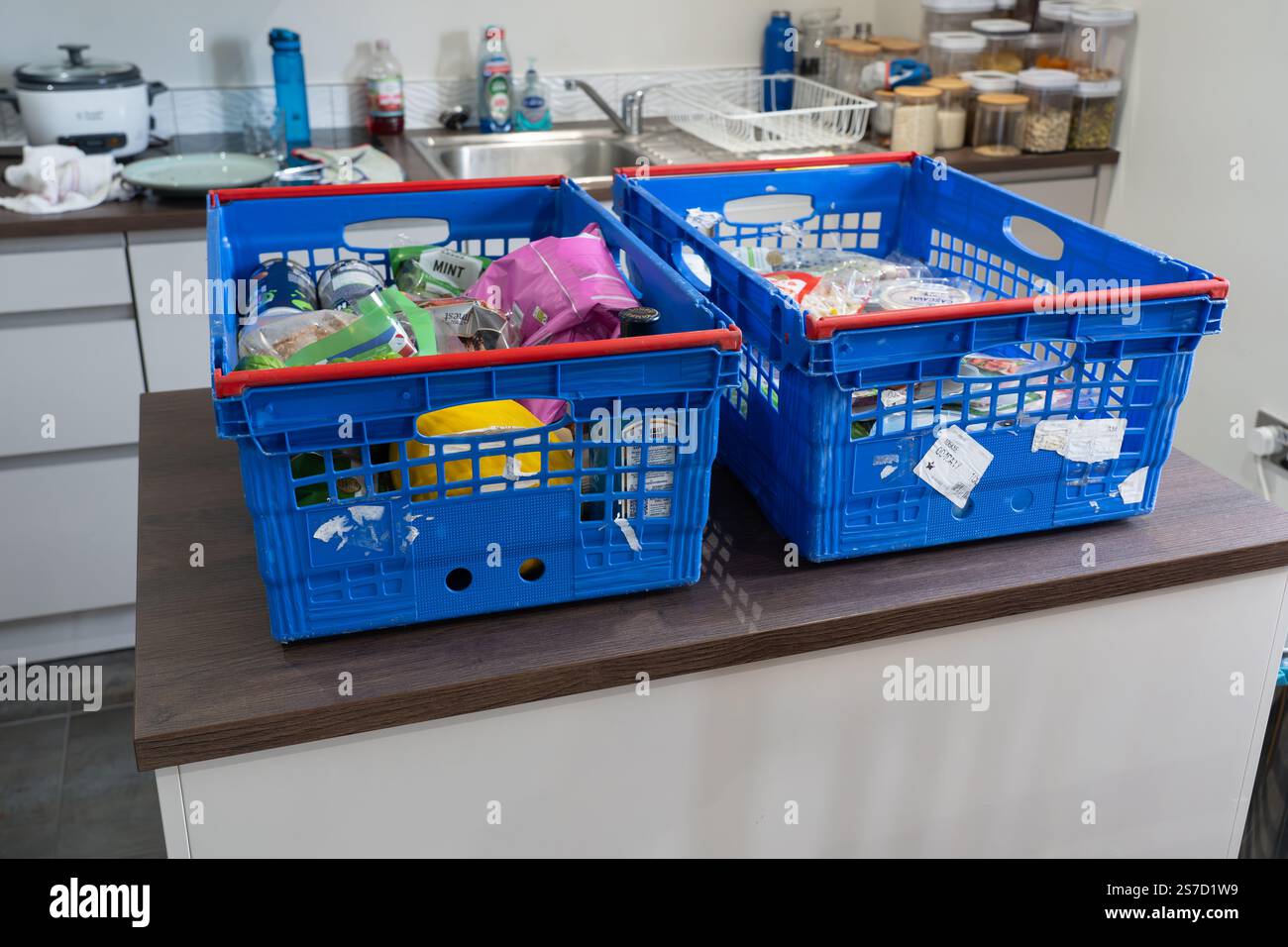 Online-Lebensmitteleinkäufe und Lebensmittellieferungen vom Tesco Supermarkt mit blauen Boxen voller Lebensmittel ohne Plastiktüten auf einer Insel in einer britischen Küche Stockfoto