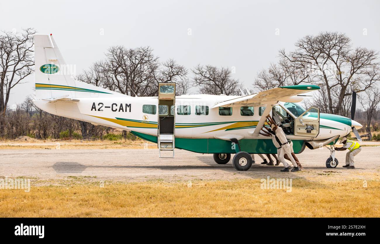 Safari-Guides schieben Touristenflugzeug mit Platten Reifen, Moremi Flugplatz, Botswana, Afrika Stockfoto