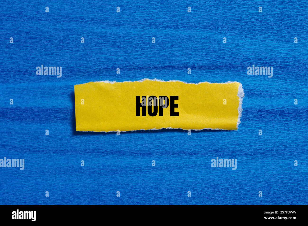 Hope Message geschrieben auf gerissenem gelbem Papierstück mit blauem Hintergrund. Konzeptuelles Hoffnungssymbol. Kopierbereich. Stockfoto