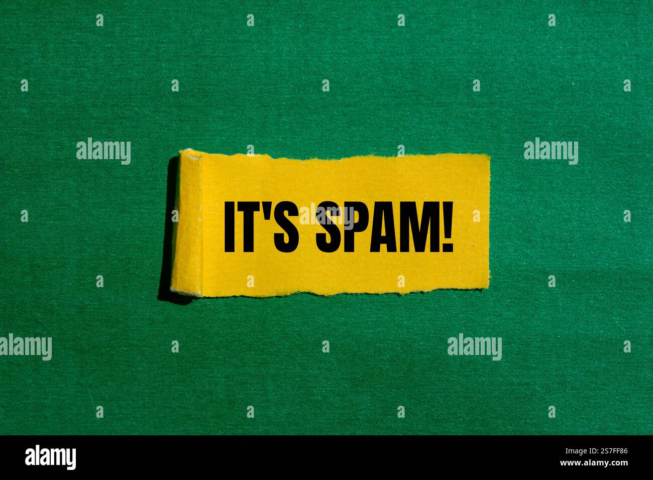 Es ist eine Spam-Nachricht, geschrieben auf gerissenem gelbem Papier mit grünem Hintergrund. Konzeptionell ist das Spam-Symbol. Kopierbereich. Stockfoto
