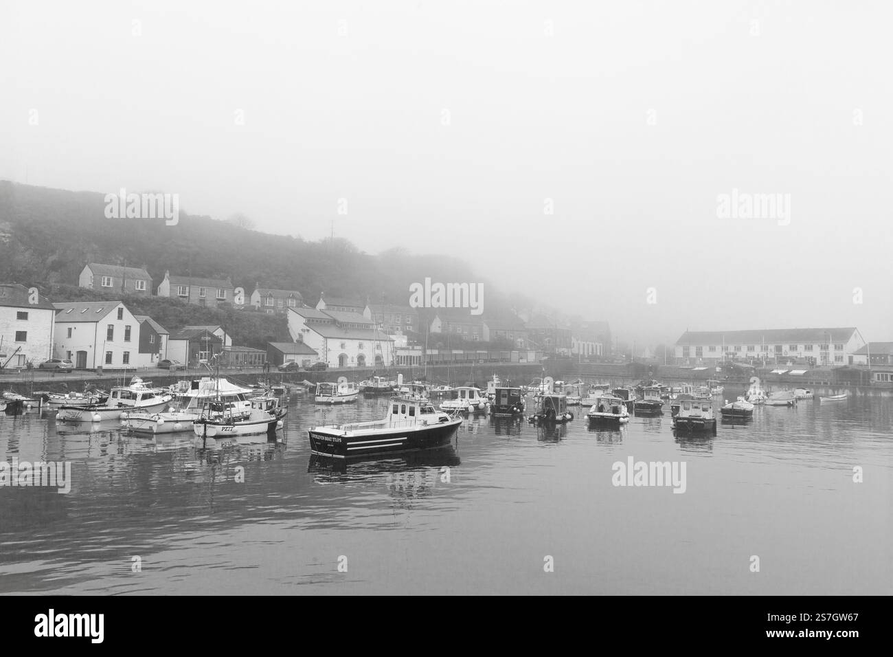 Meeresnebel umhüllt den Hafen von Porthleven bei Flut | Cornwall | Schwarz-weiß Stockfoto