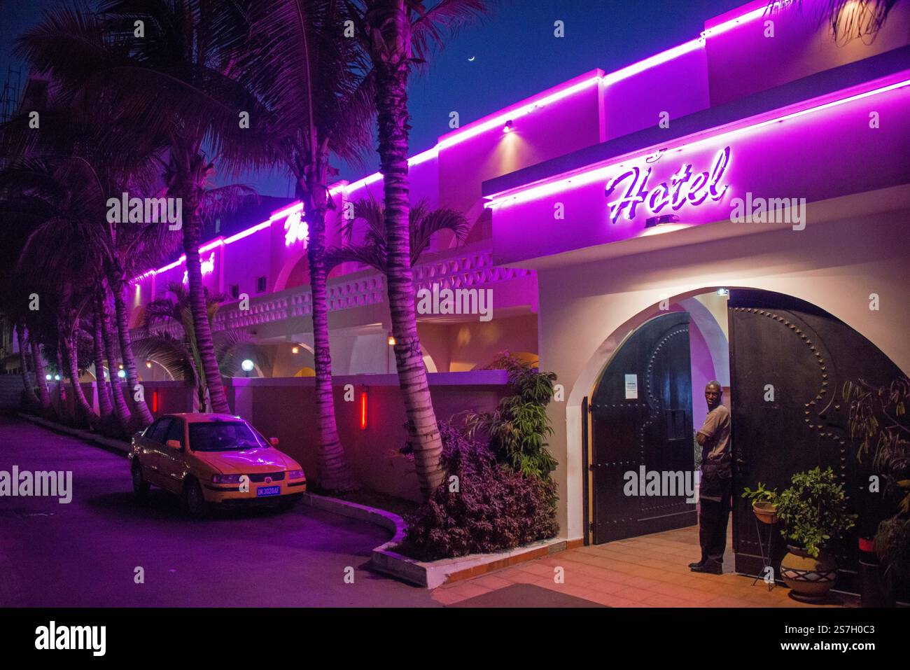 Wachmann, vor der Tür eines Hotels mit Nachtbeleuchtung, in der Gegend von Cornise in Dakar, Senegal Stockfoto