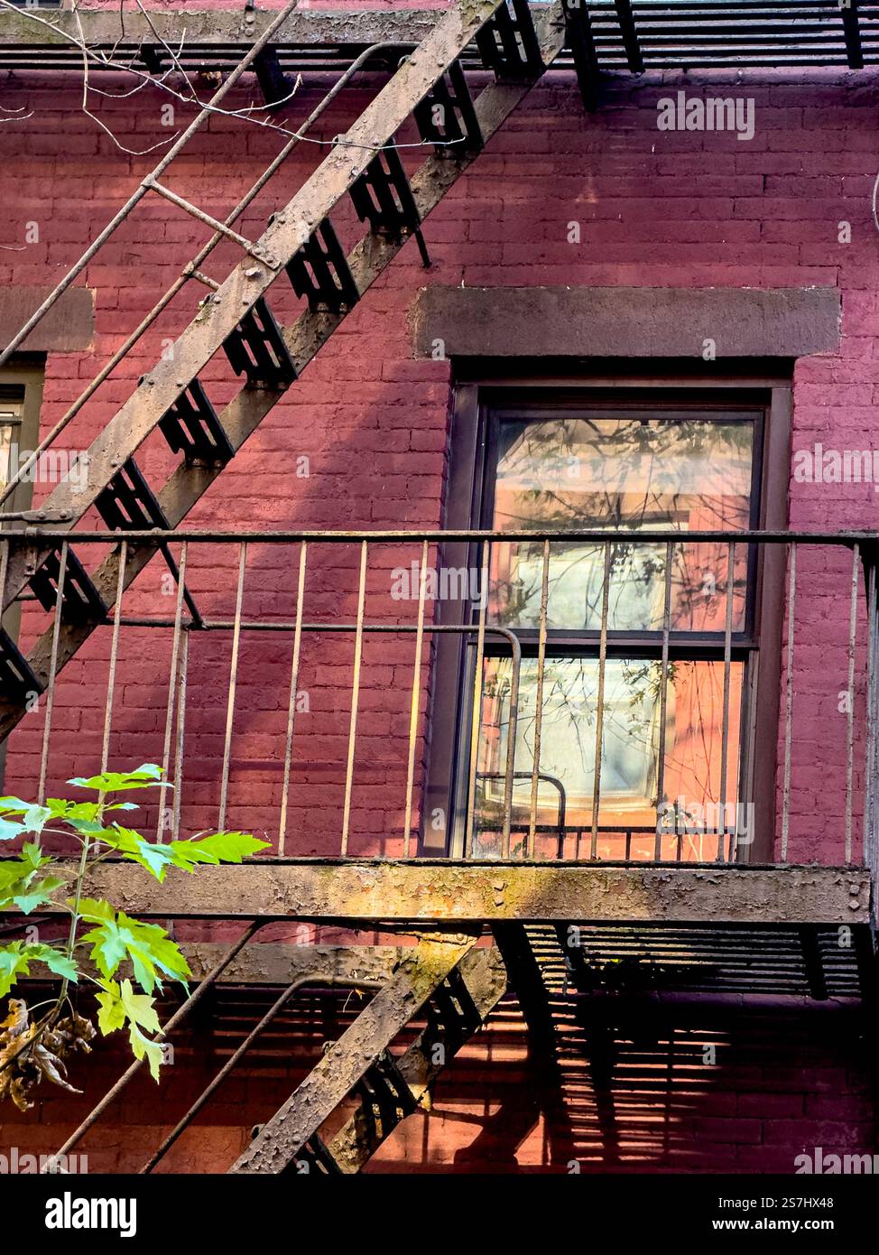 Feuer entgeht Schatten und Reflexionen in Fenstern auf typischen roten Backsteingebäuden in Greenwich Village, New York City, NY, USA - Smartphone-aufgenommenes Stockfoto