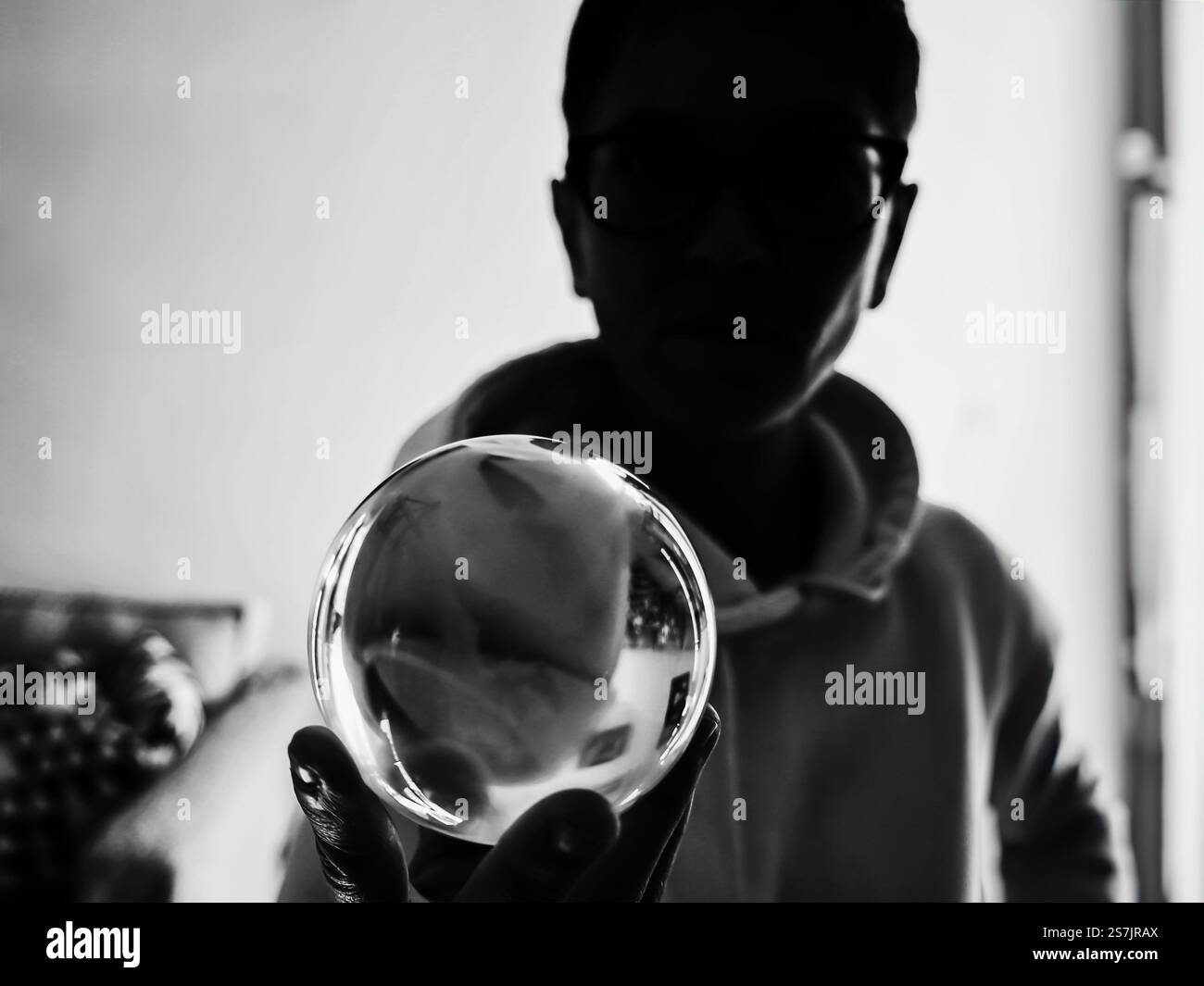 Silhouette einer Person, die eine reflektierende Glaskugel hält. Aufgenommen auf Augenhöhe, Athen Griechenland - 6. Januar 2025 Stockfoto