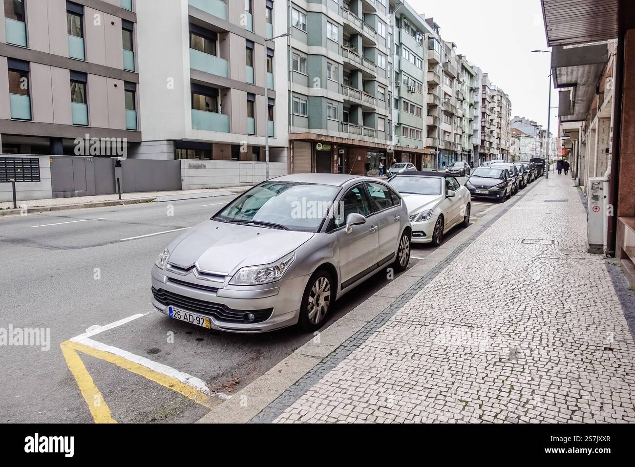 Autos parken am Straßenrand, umgeben von Wohnhäusern in einem Wohngebiet von Porto, Portugal Stockfoto