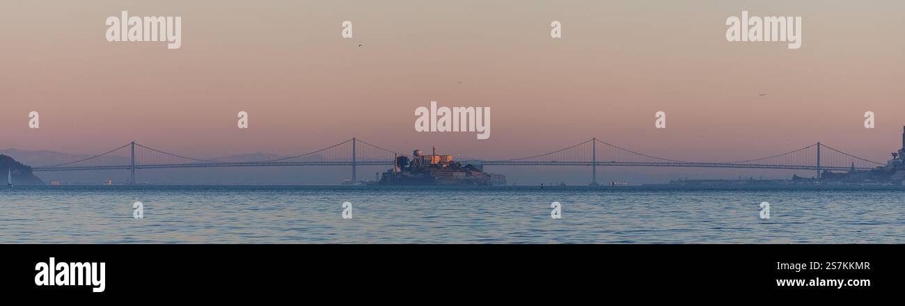 Auf der Insel Alcatraz mit der Bay Bridge im Hintergrund leuchtet das blaue und orangene Dämmerungslicht Stockfoto