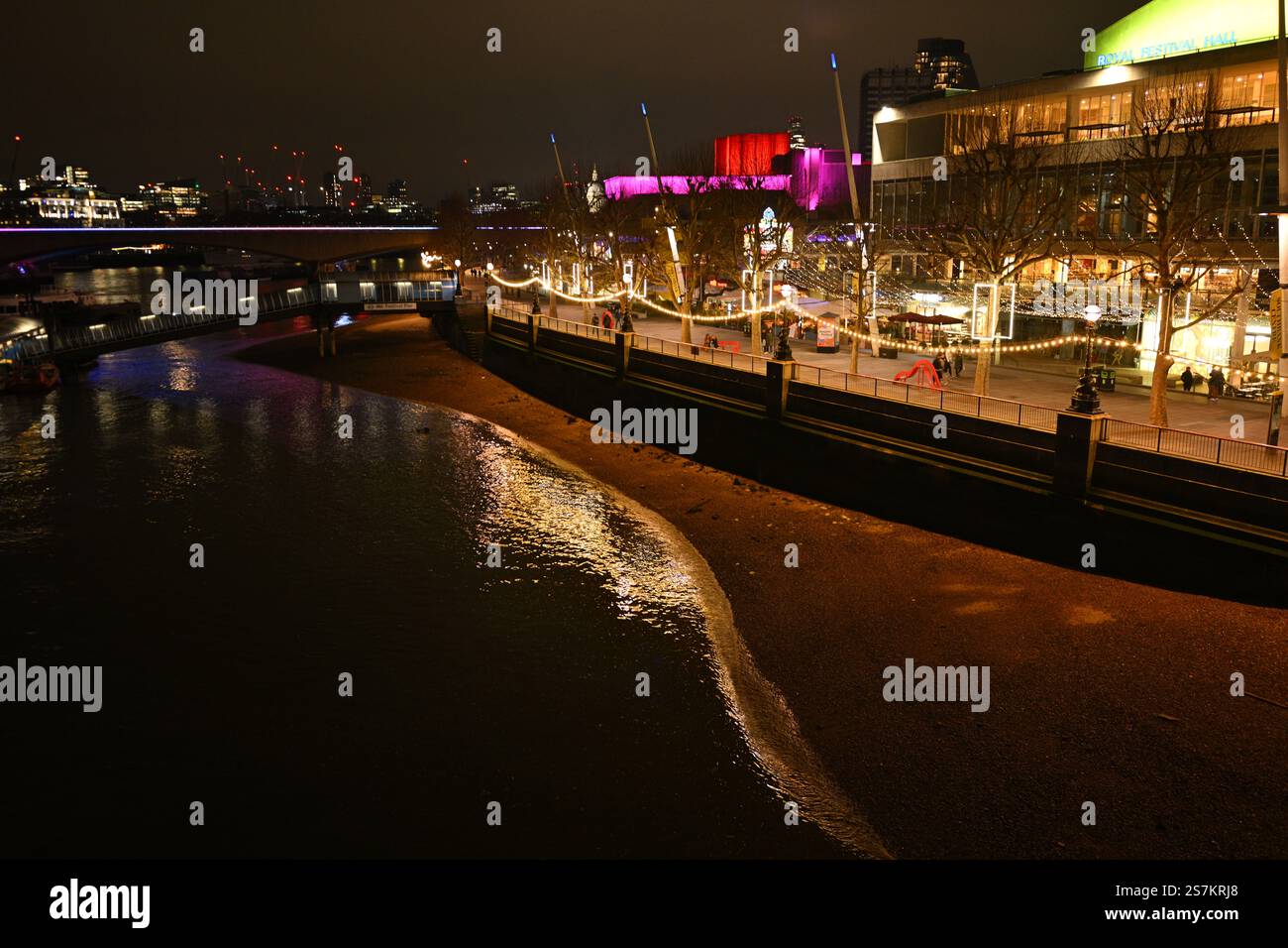 Beleuchtete Flussufer der Stadt bei Nacht mit Reflektionen und festlichen Lichtern Stockfoto