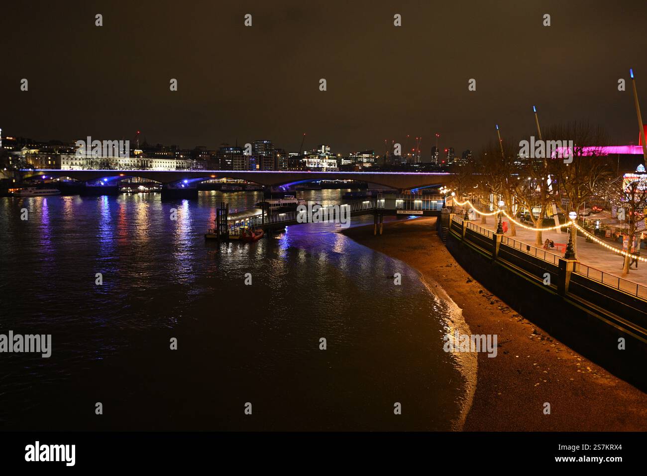 Beleuchtete Flussufer der Stadt bei Nacht mit Reflektionen und festlichen Lichtern Stockfoto