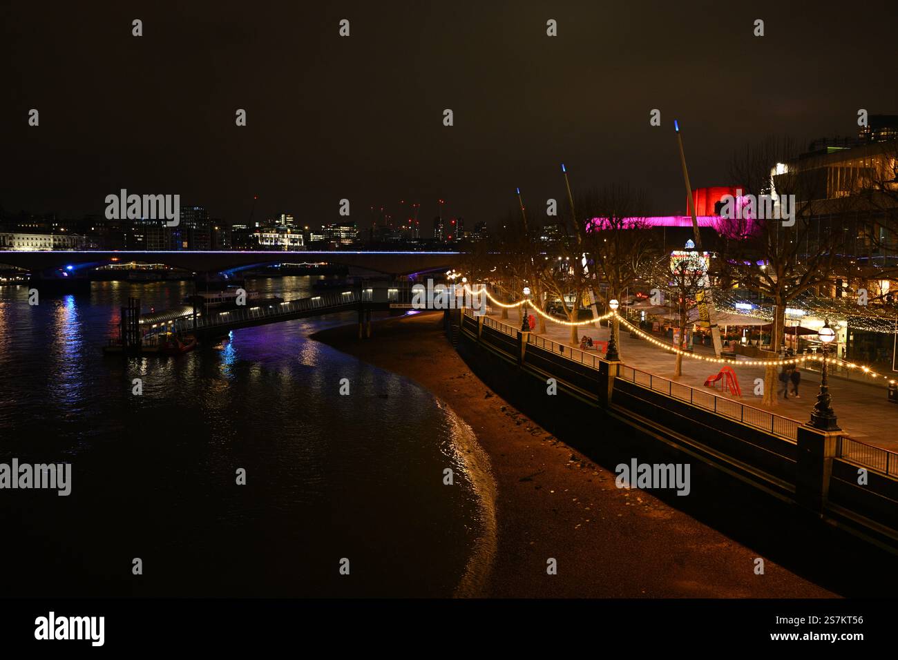 Beleuchtete Flussufer der Stadt bei Nacht mit Reflektionen und festlichen Lichtern Stockfoto