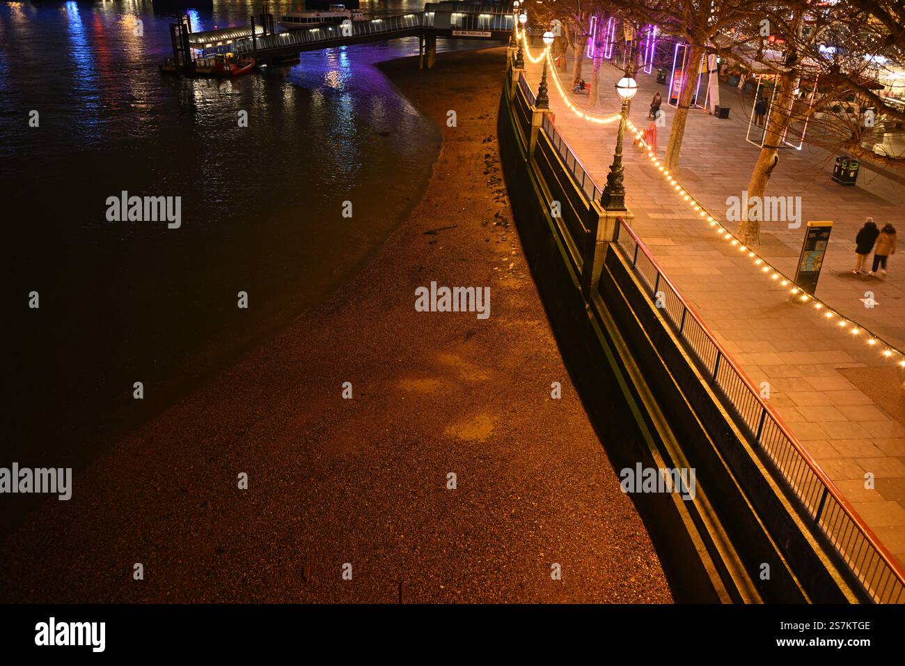 Beleuchtete Flussufer der Stadt bei Nacht mit Reflektionen und festlichen Lichtern Stockfoto