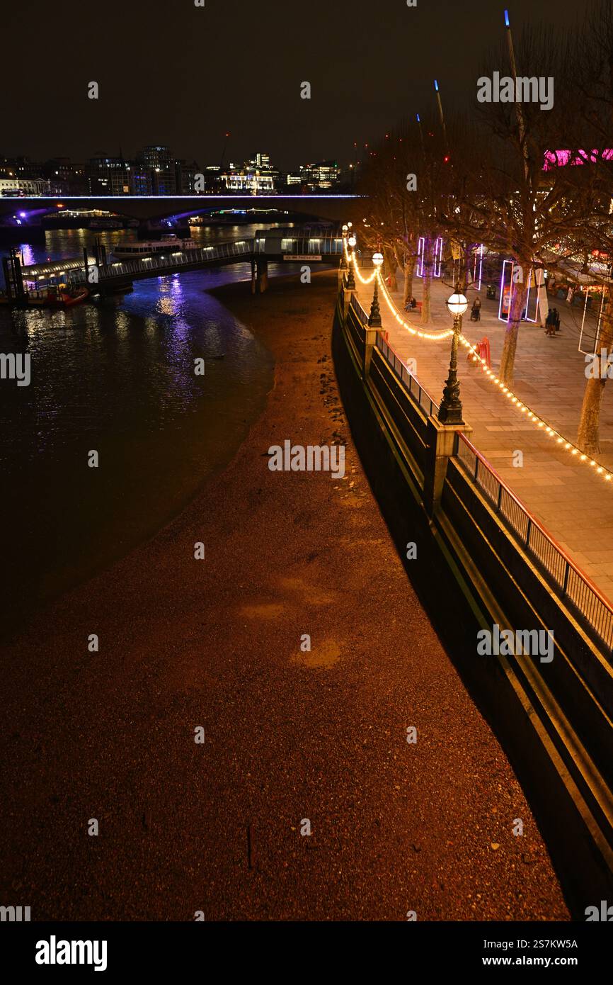 Beleuchtete Flussufer der Stadt bei Nacht mit Reflektionen und festlichen Lichtern Stockfoto