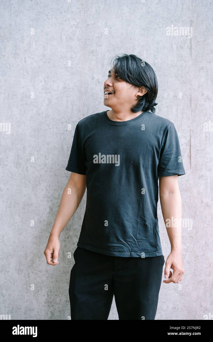 Junger Mann in schwarzem T-Shirt, der mit neugierigem Ausdruck aufblickt. Stockfoto