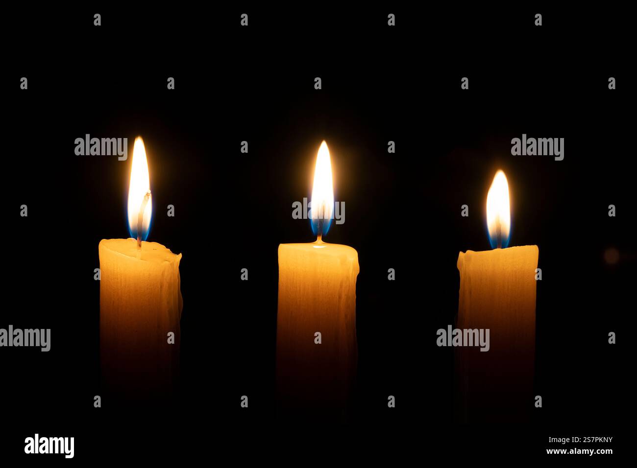 Eine orangene Kerze brennt im Dunkeln auf schwarzem Hintergrund. Das Konzept von Erinnerung und Trauer. Stockfoto