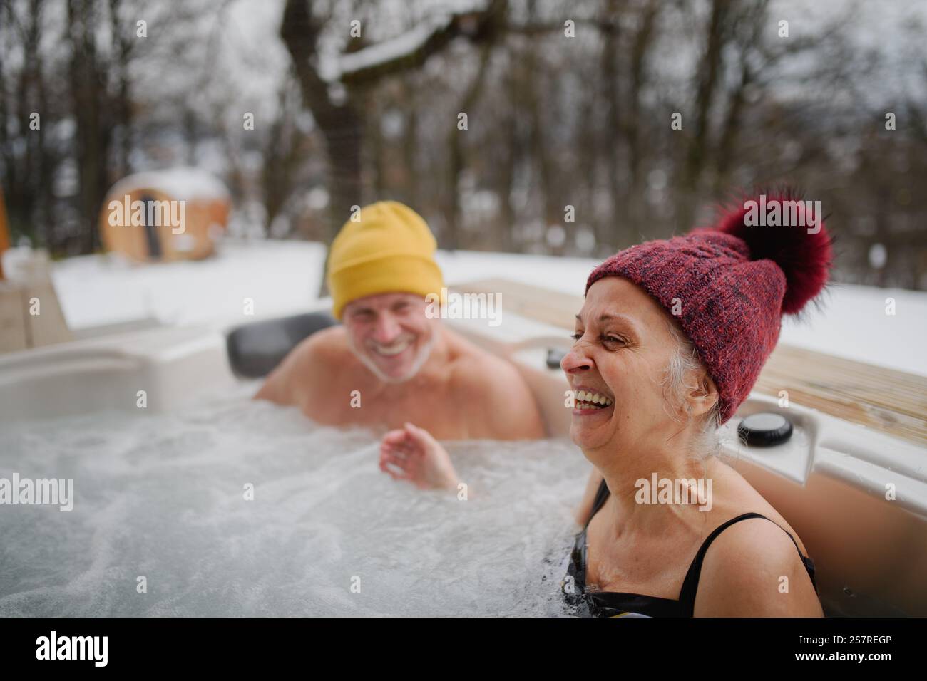 Seniorenpaar baden im Wannen-Whirlpool an kalten Wintertagen. Romantischer Wellness-Kurzurlaub mit Spa am Valentinstag-Wochenende. Stockfoto