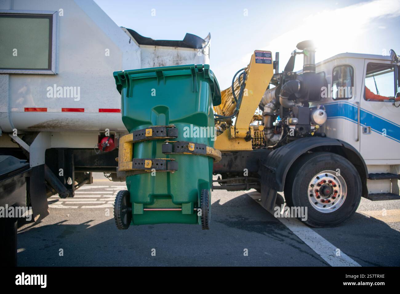 Grüner Abfallbehälter für Wohnzwecke wird angehoben, um organische Abfälle in einem Lkw zu entsorgen Stockfoto