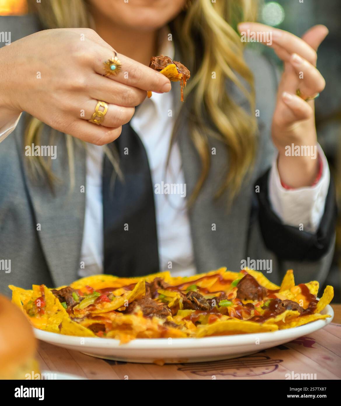 Eine junge Frau isst Nachos mit Käse in einem Restaurant Stockfoto