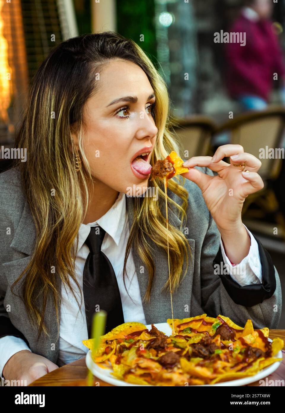 Eine junge Frau isst Nachos mit Käse in einem Restaurant Stockfoto