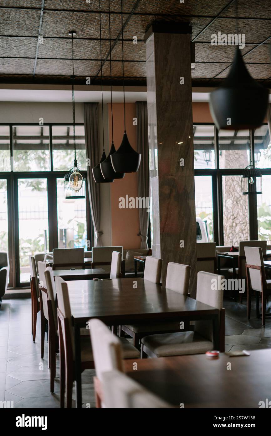 Geräumiger Speisesaal mit großen Fenstern und moderner Beleuchtung. Stockfoto