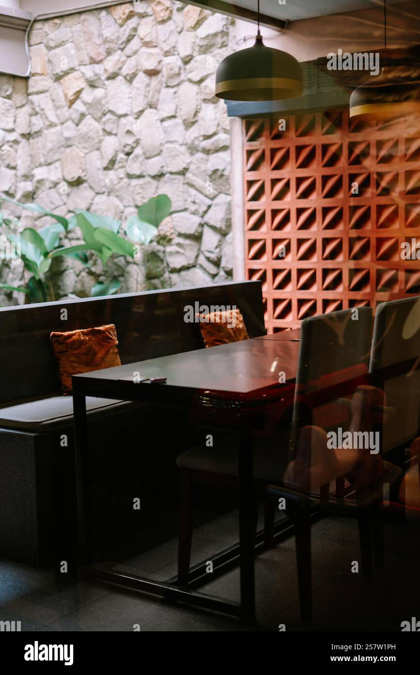 Gemütliche Caféecke mit Tisch, Sitzbänken und dekorativer Wand. Stockfoto