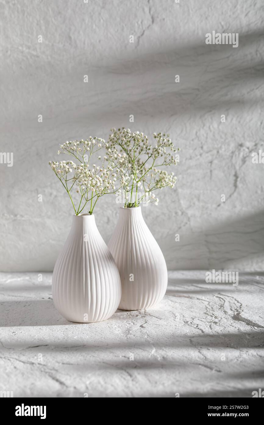 Steinhintergrund und weiße Vase mit Blumen. Minimalistische Szene als Hintergrund mit Platz für Text. Stockfoto