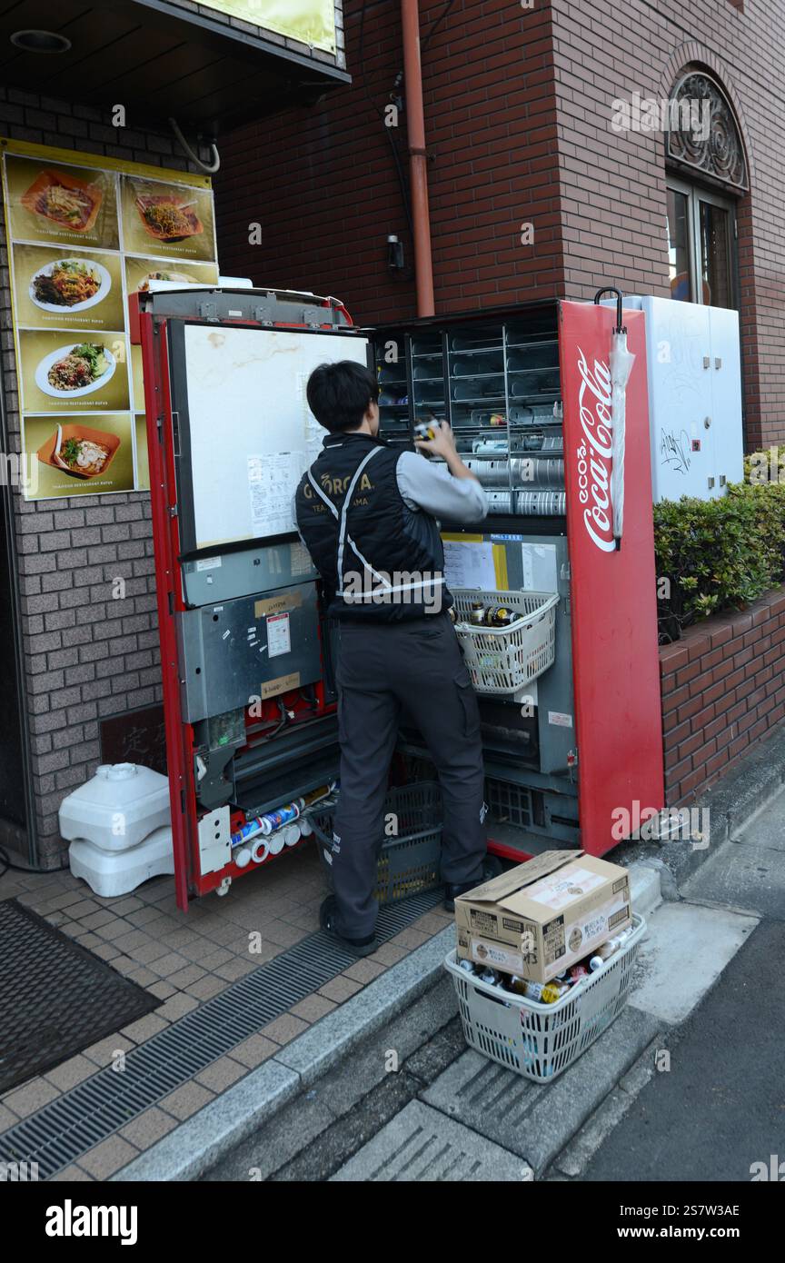 Ein Mann, der einen Coca-Cola-Automaten in Omiya, Saitama, Japan lädt. Stockfoto