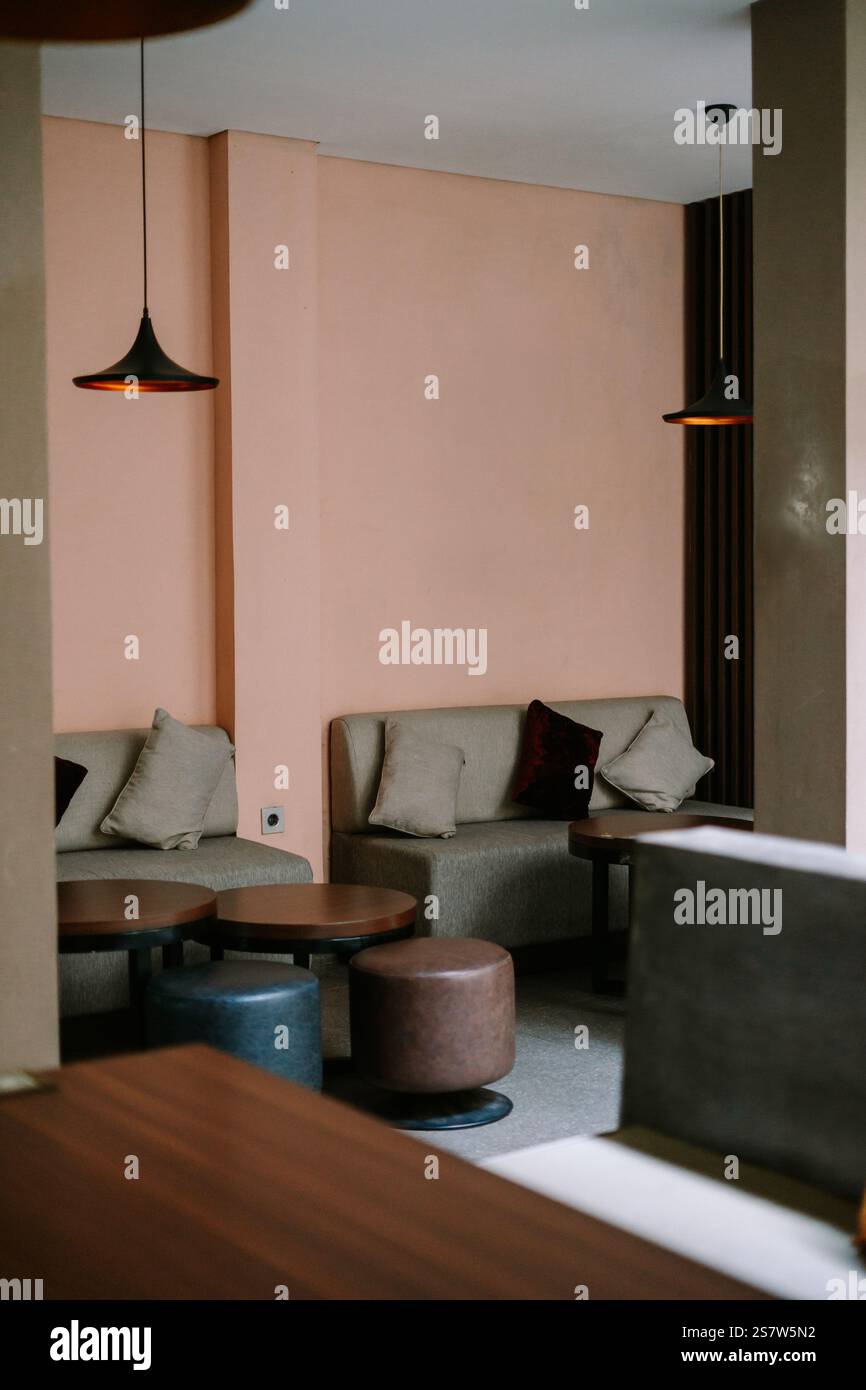 Moderne Lounge mit sanften pinkfarbenen Wänden, bequemen Sitzgelegenheiten und einfacher Einrichtung. Stockfoto