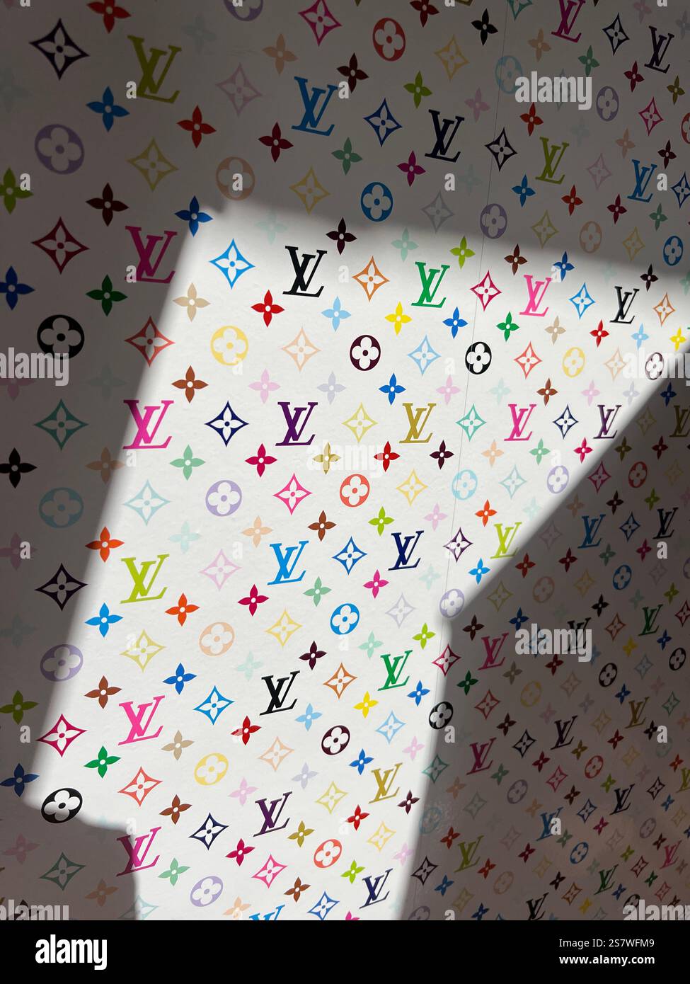 Farbenfrohes Louis Vuitton Logo mit Monogramm. Licht und Schatten auf der Tapete. LV künstlerische, vertikale Ansicht. Weltberühmtes, anerkanntes Fashion-Logo Stockfoto