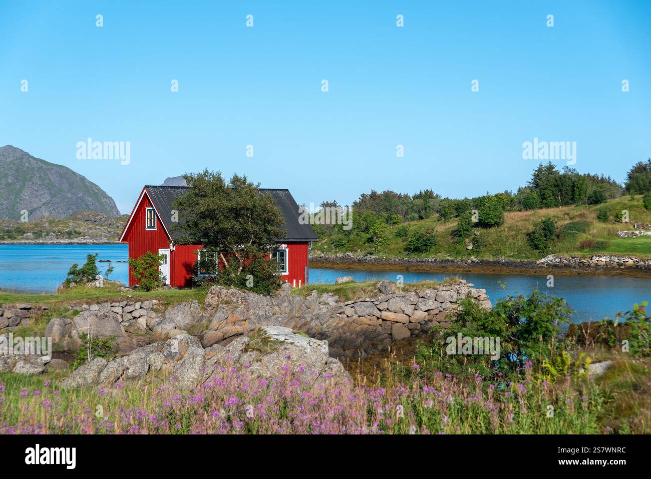 Blick auf die Landschaft der Skotnesosen Bucht mit traditionellem rotem Fischerhaus, genannt rorbu, Ballstad, Lofoten, Norwegen, Europa Stockfoto