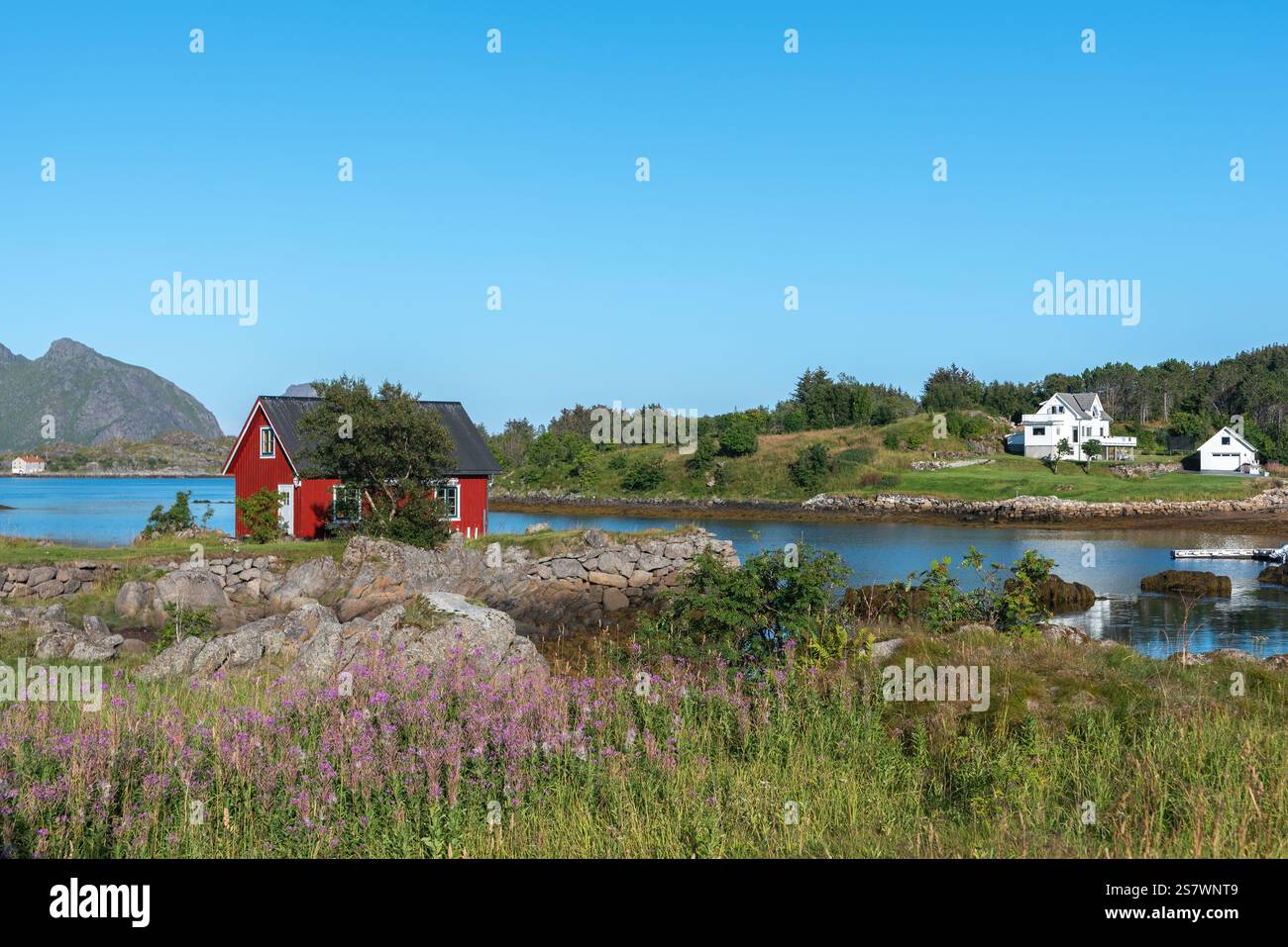Blick auf die Landschaft der Skotnesosen Bucht mit traditionellem rotem Fischerhaus, genannt rorbu, Ballstad, Lofoten, Norwegen, Europa Stockfoto