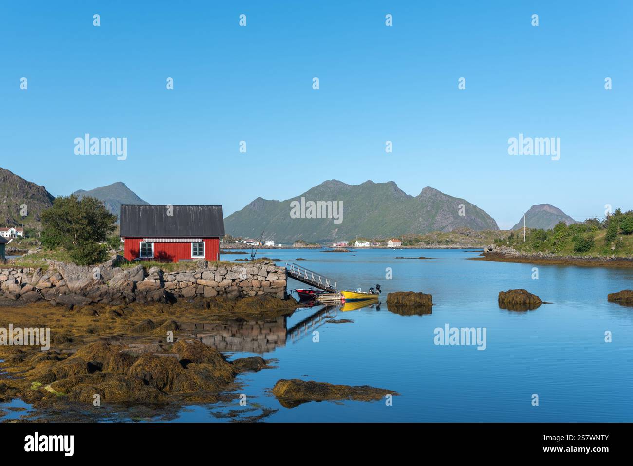Blick auf die Landschaft der Skotnesosen Bucht mit traditionellem rotem Fischerhaus, genannt rorbu, Ballstad, Lofoten, Norwegen, Europa Stockfoto