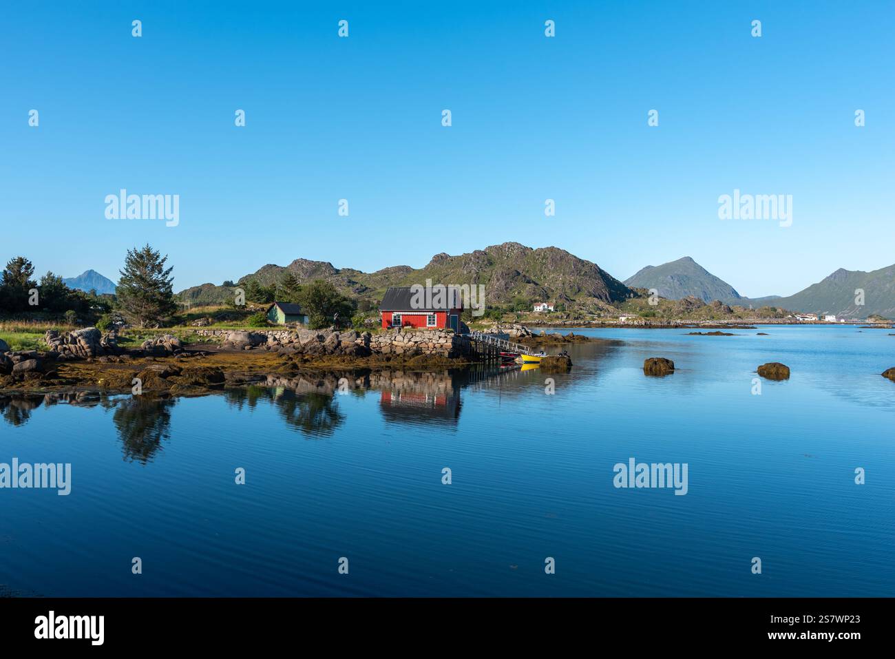 Blick auf die Landschaft der Skotnesosen Bucht mit traditionellem rotem Fischerhaus, genannt rorbu, Ballstad, Lofoten, Norwegen, Europa Stockfoto