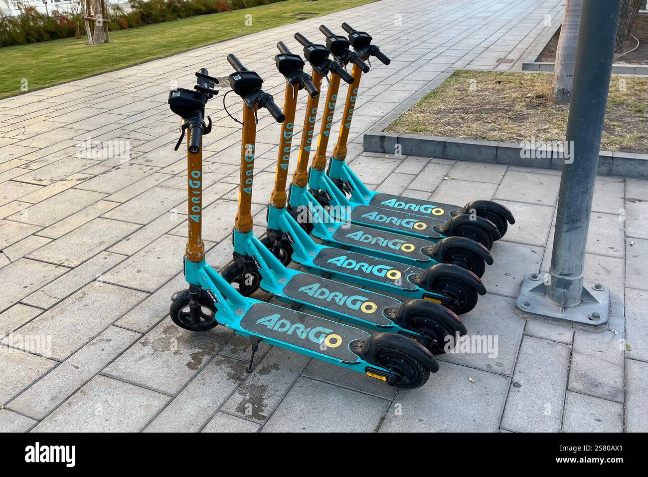 Reihe geparkter Adrigo Elektroroller (E-Scooter) in Costa Adeje. Teneriffa, Kanarische Inseln, Spanien. Januar 2025. Stockfoto