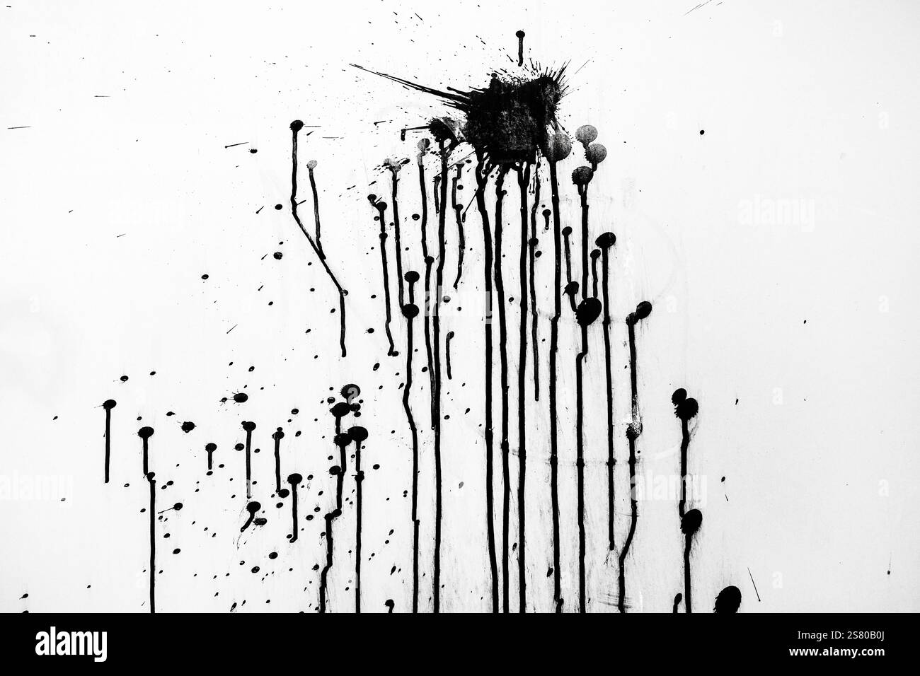 Schwarze Lackspritzer über weiße Wandfläche als Hintergrund Stockfoto