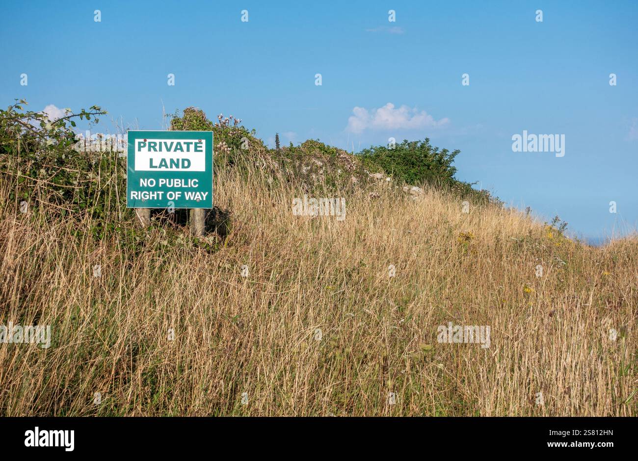 Warnschild, das an einem sonnigen Tag auf privatem Land ohne öffentlichen Zugang inmitten von hohem Gras steht Stockfoto