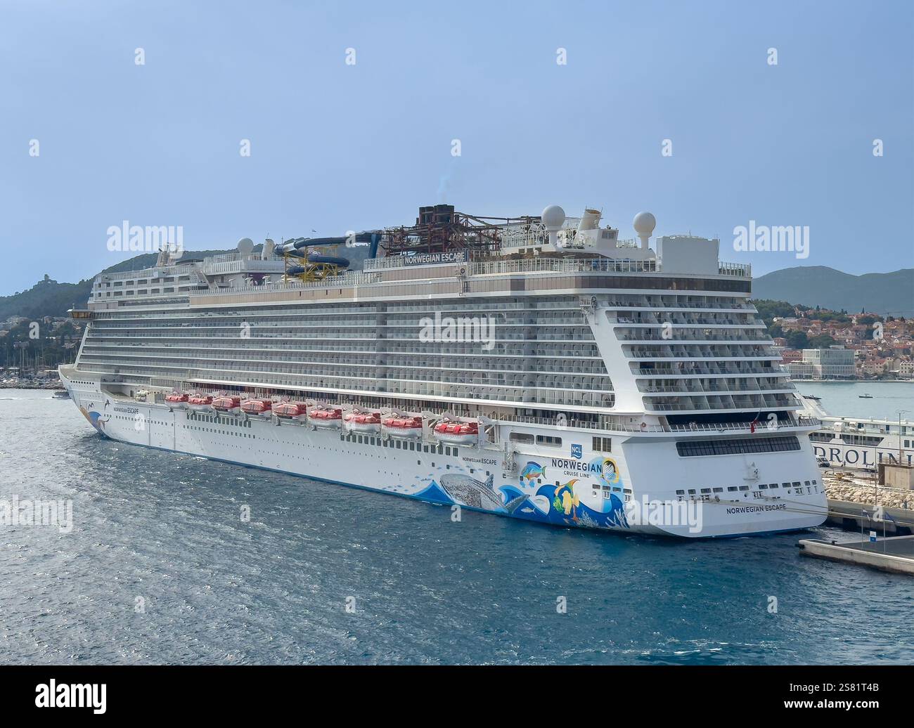 Split, Kroatien - 1. Juli 2024: Großes norwegisches Fluchtkreuzschiff im Hafen, Nahaufnahme, Fährhafen Jadrolinia mit Schiff dahinter. Unter blauem Himmel Stockfoto