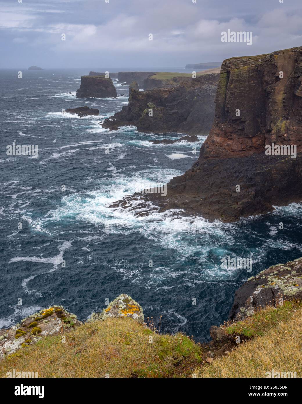 Ein Sturm über den vulkanischen Klippen von Eshaness, Shetland, Schottland, erzeugt massive Wellen und turbulente Meere rund um die Meeresstapel. Stockfoto