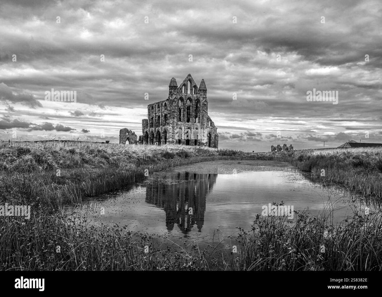 Reflexionen der gotischen, historischen und wunderschön ruinierten Whitby Abbey. Im Spiegel wie ein Teich. Die Wolken sammeln sich über Türmen Stockfoto
