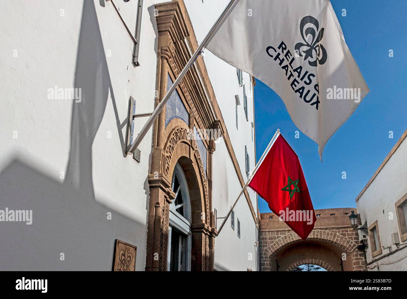 Der Eingang zu einem Relais & Châteaux Hotel in Essaouira, Marokko, mit der marokkanischen Flagge und der Hotelflagge. Stockfoto