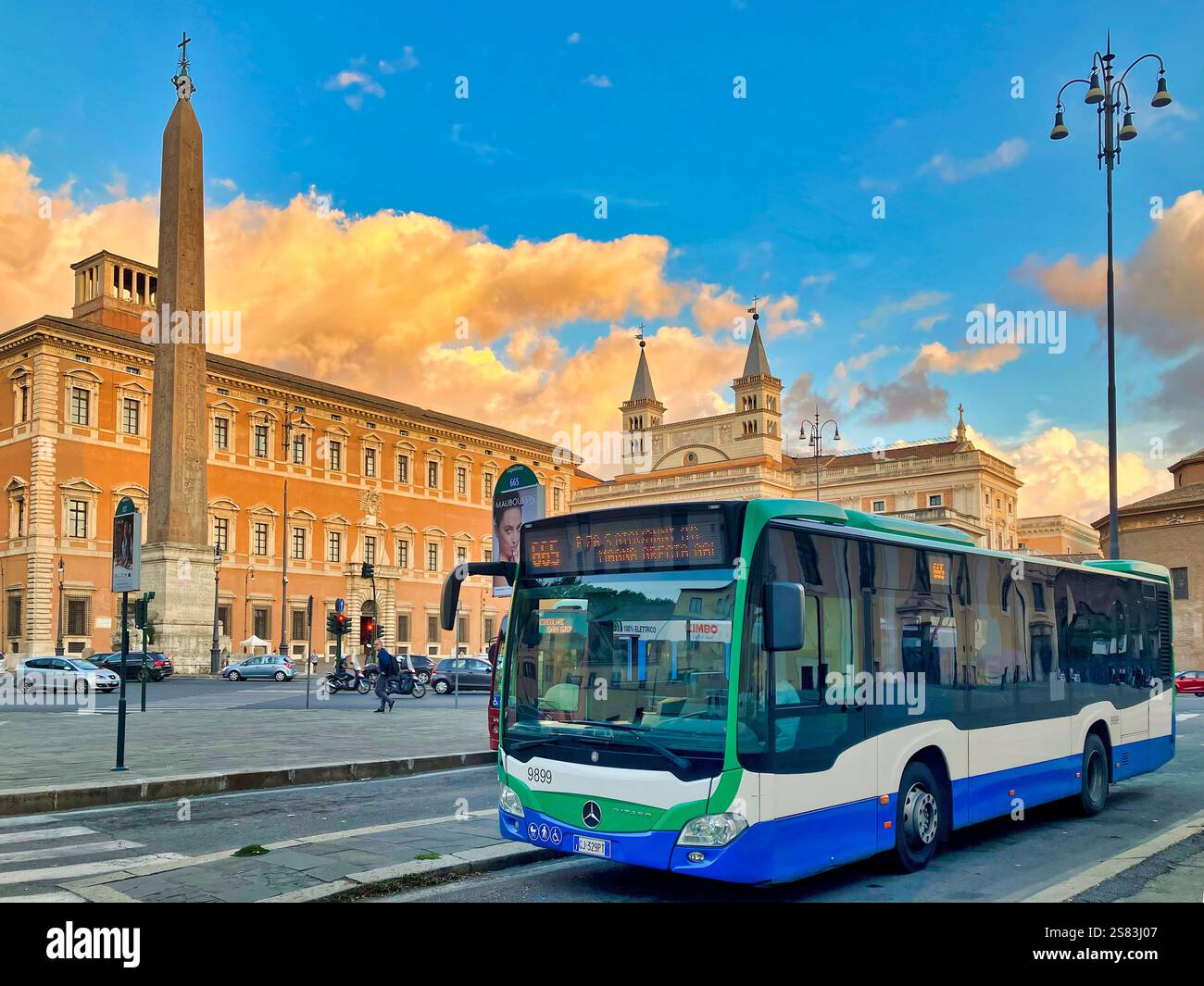 Ein Stadtbus parkt an der Piazza San Giovanni in Laterano, Rom, Italien, mit dem Lateranobbelisken und der Basilika im Hintergrund während des Sonnenuntergangs. - Smartphone-aufgenommenes Stockfoto