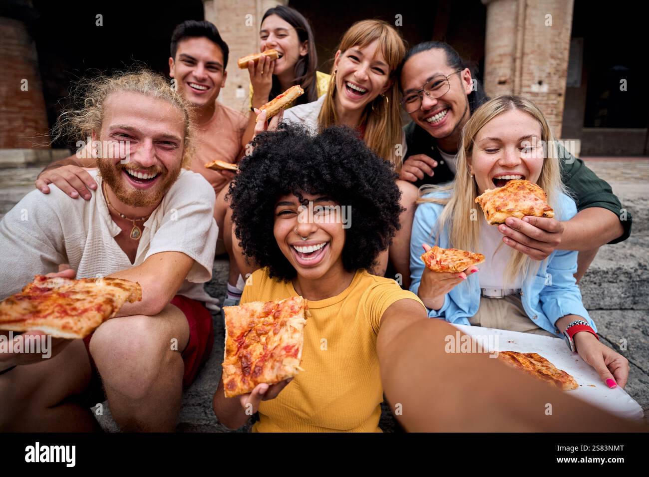 Lustige Gruppe junger Leute und sie haben Spaß beim Pizza essen in der touristischen Stadt Stockfoto
